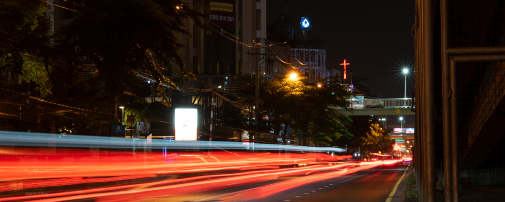 valomaalattu valokuva Thaimaan öideltä kadulta, jossa kauempana näkyy punainen risti